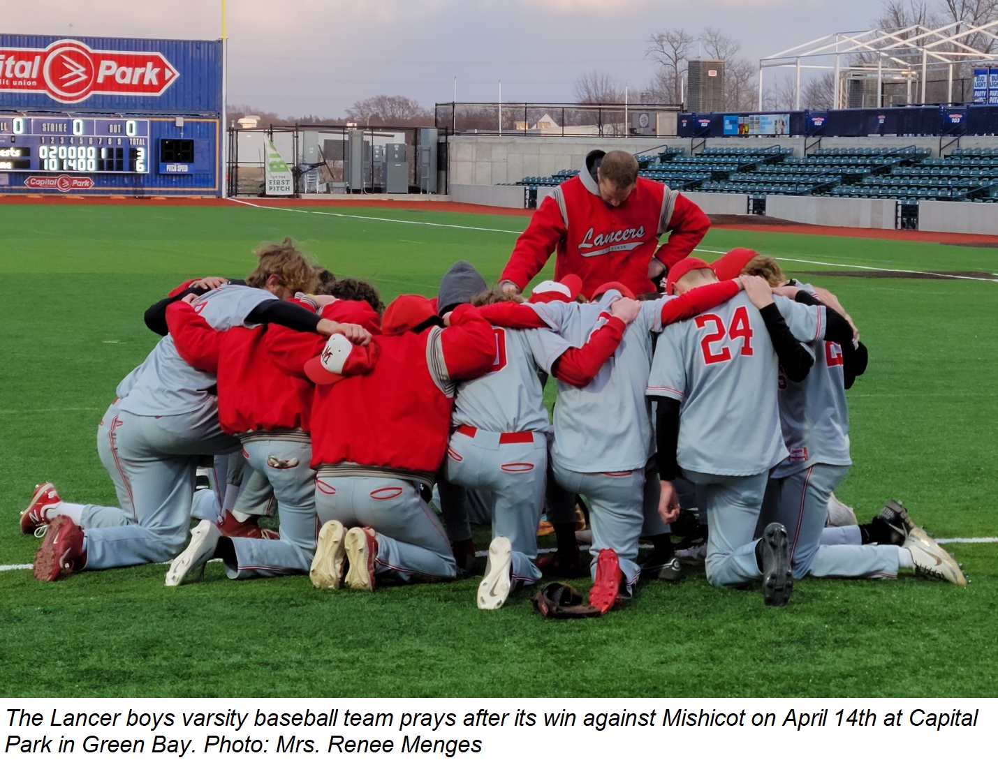 The Lancer varsity baseball team prays after its win against Mishicot at Capital Park in Green Bay on April 14th.