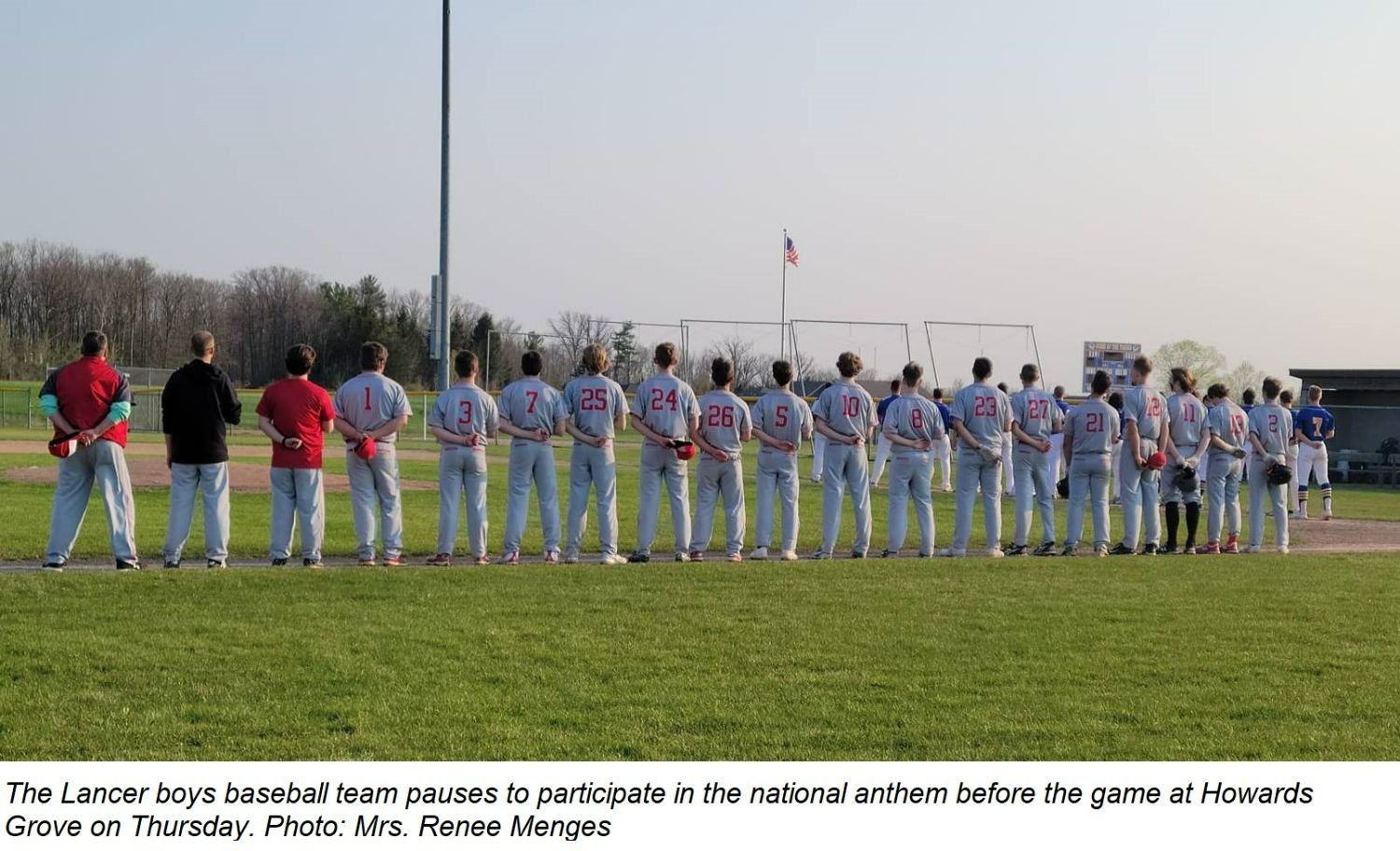 The Lancer boys baseball team pauses for the National Anthem at the start of the game Thursday at Howards Grove.